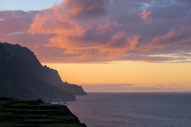 Deniz kenarında güzel bir gün batımı. Güzel bir doğa geçmişi var. Dağlar ve dalgalar. Güzel gökyüzü. 