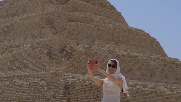 穿着白衣的女人正在自拍 背景是Djoser Step 考古遗存于埃及 非洲的萨卡拉墓地 旅行旅游概念 — 图库视频影像