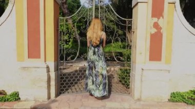 Uzun saçlı kızıl saçlı kadın uyandı ve parkın kapısını açtı. Valencia 'daki Halk Monforte Parkı. Yavaş çekim videosu.