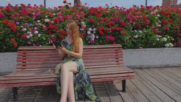 Червона Жінка Довгим Волоссям Сидить Лавці Читає Електронну Книжку Дівчинка — стокове відео