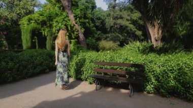 Uzun saçlı kızıl saçlı kadın parkta uyanıyor. Valencia 'daki Halk Monforte Parkı. Yavaş çekim videosu.