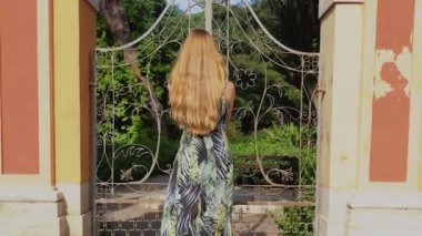 Uzun saçlı kızıl saçlı kadın uyandı ve parkın kapısını açtı. Valencia 'daki Halk Monforte Parkı. Yavaş çekim videosu.