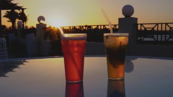 日没時に海辺のカクテル2杯 2つのカクテルがグラステーブルの上に立っている ガラスの上の美しい反射 4Kスローモーションビデオ — ストック動画