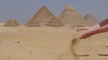 Kadın elleri bir kumla ve Mısır 'daki Büyük Giza Piramitleriyle birlikte. Kum tutan bir kız.