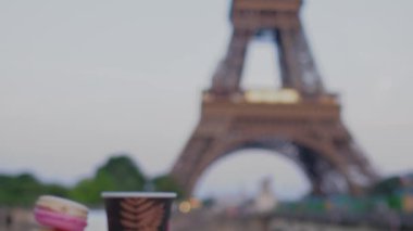 Eiffel Kulesi 'nde Fransız kurabiyeleri ve parlak arka planda bir kahve. Gün batımından sonra alacakaranlık. Yavaş çekim videosu.