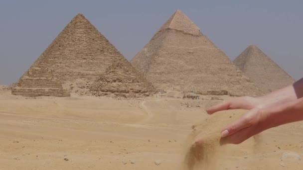 女性の手は砂とエジプトのギザの大ピラミッドです 女の子は砂を持っている — ストック動画