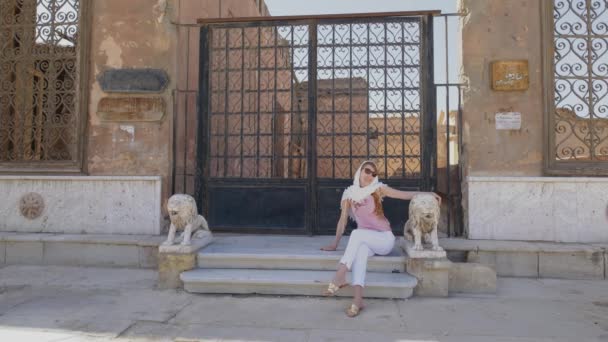 女性は古いアラビアの装飾を持つ階段の近くに座っています 観光スポット カイロ エジプト — ストック動画