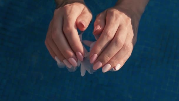 女性的手与美丽的天然粉红优雅的指甲 美丽的妇女指甲 水和护肤的概念 美甲沙龙 慢动作4K视频 — 图库视频影像