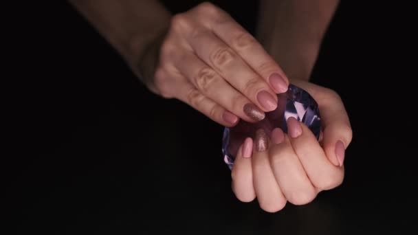 4K视频特写的粉红指甲与火花在照相馆 与黑色背景 手被放置在一个巨大的假紫色钻石上 灯光逐渐改变方向 — 图库视频影像