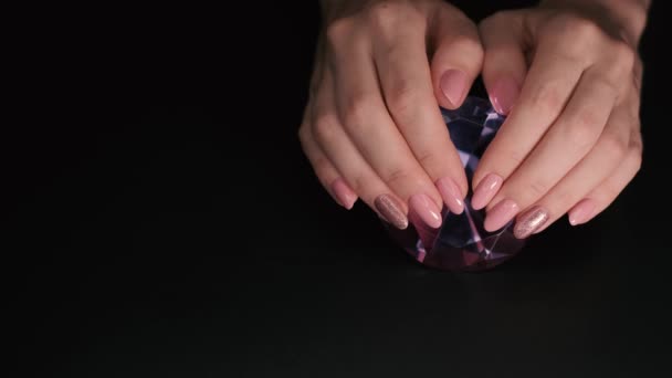 4K视频特写的粉红指甲与火花在照相馆 与黑色背景 手被放置在一个巨大的假紫色钻石上 灯光逐渐改变方向 — 图库视频影像