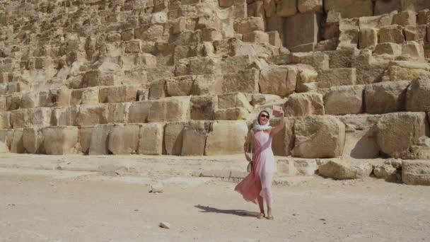 在这段视频中 一个女人用一个简单而迷人的场景拍摄了一个自拍 与壮观的吉萨大金字塔相映成趣 体现了旅行和旅游的理念 — 图库视频影像