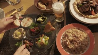Mısır yemeği masanın üzerindedir. Bıçaklı kadın elleri ekmeğe sos koyuyor. Arap mutfağına yakın çekim. Bir restoranda tandır roti ekmeği. 
