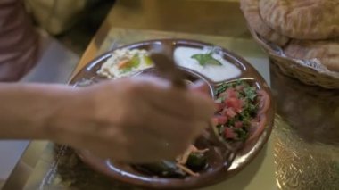 Mısır yemeği masanın üzerindedir. Çatallı bir kadın, salata topluyor. Restoranda. Arap mutfağı.