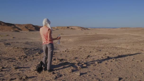このビデオでは エジプトの熱い砂漠の中で女性が喉の渇きを癒し 彼女がこの魅惑的な土地を通って旅に出るように暑い天気の概念を強調しています — ストック動画