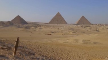 Giza 'nın görkemli piramitlerinin ufukta göründüğü uçsuz bucaksız altın kumların arasında unutulmaz bir yolculuğa çıkın. Büyüleyici bir deve kervanı güneşin altında ritmik bir şekilde yürüyor..
