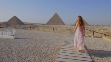 Mısır 'daki Giza Piramitleri' ne doğru yürüyen genç kadının arka görüntüsü. Turist seyahat kavramı. 