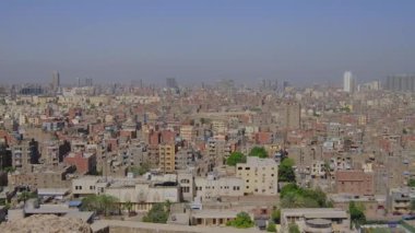 Yüksek çözünürlüklü bir 4K videosu hala Mısır, Kahire 'de, yoğun binalar, tarihi İslami mimari ve açık mavi gökyüzü altında minareler ile geniş bir şehir manzarası sergiliyor..