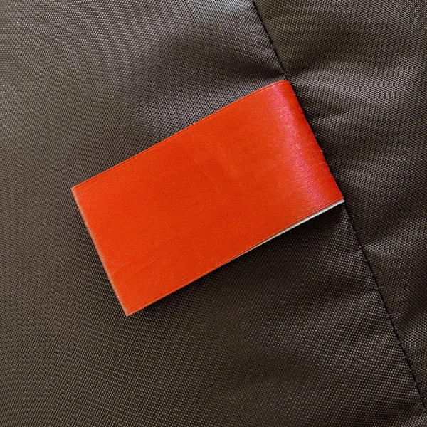 A red blank label on a brown garment or soft garment. Reminder or place for logo