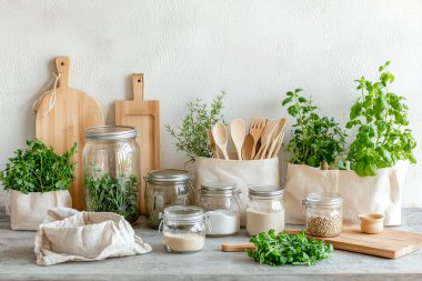 Cam kavanozlar, bambu kaplar, yeniden kullanılabilir pamuk torbaları, ahşap raflar ve saksı bitkileri gibi çevre dostu aksesuarların yer aldığı şık bir sıfır atık mutfağı.. 