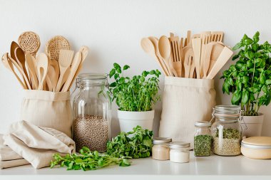 Cam kavanozlar, bambu kaplar, yeniden kullanılabilir pamuk torbaları, ahşap raflar ve saksı bitkileri gibi çevre dostu aksesuarların yer aldığı şık bir sıfır atık mutfağı.. 