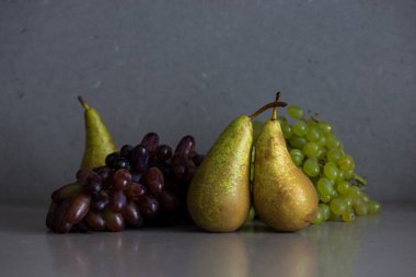 Autumn fruit still life with pears and grapes on the grey background clipart