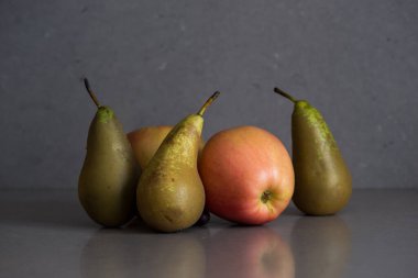 Gri arka planda elmalar ve armutlarla dolu sonbahar meyveleri.