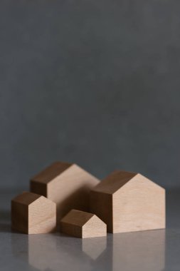 Gri arka planda minyatür evler. Tepede yer alan emlak kavramı