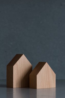 Gri arka planda minyatür evler. Tepede yer alan emlak kavramı