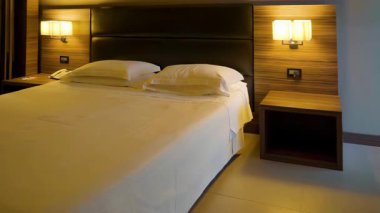 Ilık aydınlatma, İtalya 'daki misafirler için davetkar bir ortam yaratan, düzenli, çift kişilik ve modern ahşap döşemelere sahip şık bir otel odasını aydınlatıyor.