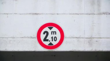 Bir beton duvara asılmış yükseklik sınırlaması işareti 210 metrelik maksimum açıklık gösteriyor. Bu işaret İtalya 'da siyah sembollü kırmızı bir daire içeriyor.