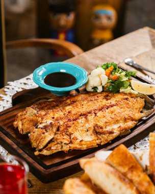 Sebzeli ızgara balık, ahşap tabakta, soya sosuyla servis ediliyor.