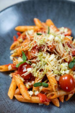 Parmesan peynirli makarna, taze fesleğen ve vişneli domates hazır.