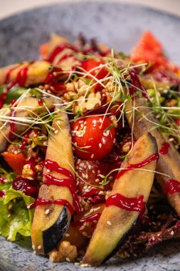 Kızarmış patlıcanlı salata, domates, ceviz, susam tohumu ve soslu nar tohumu ve mikro yeşillikle süslenmiş.