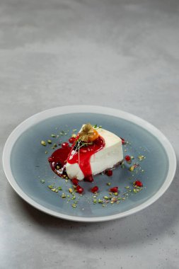 Meyve ve fındıkla süslenmiş bir tabakta servis edilen çilek soslu leziz cheesecake.