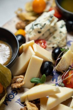 Bal, üzüm, fındık ve fizsalis eşliğinde çeşitli peynir çeşitleri olan lezzetli peynir tahtası.