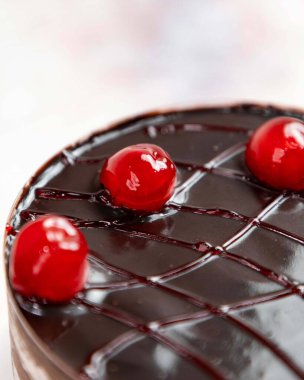 Çikolatalı pasta, üzerinde parlak çikolata jölesi ve kirazlar var. Lezzetli tatlılarla kutlama kavramını gösteriyor.