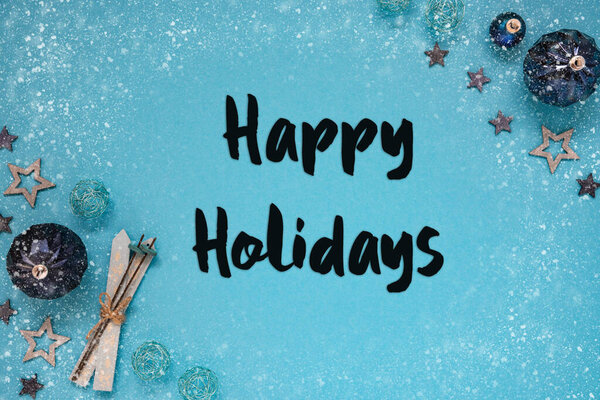 Рождественская открытка с английским словом Happy Holidays. Бирюзовый рождественский фон с украшением, как шары, звезды, лыжи и снежинки.