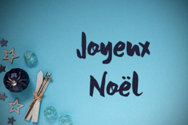 Joyeux Noel 'le Noel Kutlama Kartı Mutlu Noeller demek. Turkuaz ve mavi soğuk Noel arkaplanı süslemeler ve balo, yıldızlar ve kayak gibi şenlikli dekorasyonlar..