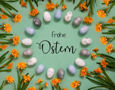 Flat Lay With English Text Frohe Ostern Means Happy Easter. Easter Egg Decoration With Orange Spring Flowers. Light Green Paper Background.