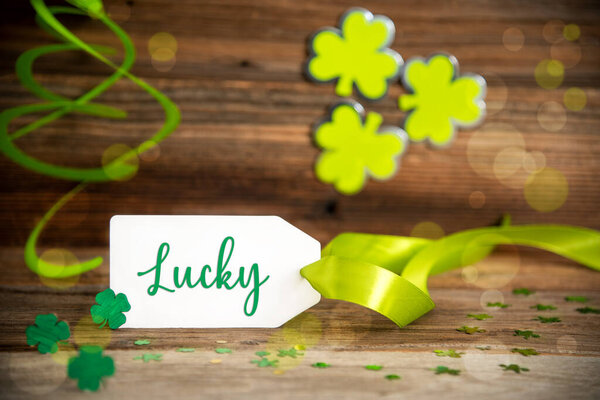 White Label with English Lucky. Украшение дня Святого Патрика зеленым трилистником и клевером. Деревянный винтажный фон с праздничной лентой.