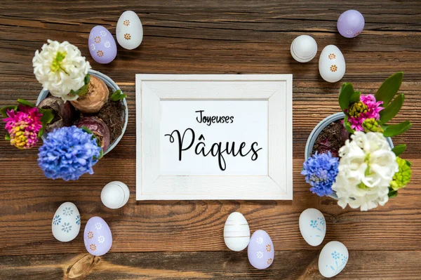 复活节平铺 画框与法语文本乔依斯帕克斯意思是复活节快乐 有复活节彩蛋装饰和装饰品的花朵 具有木制 古色古香背景的百合花排列 — 图库照片
