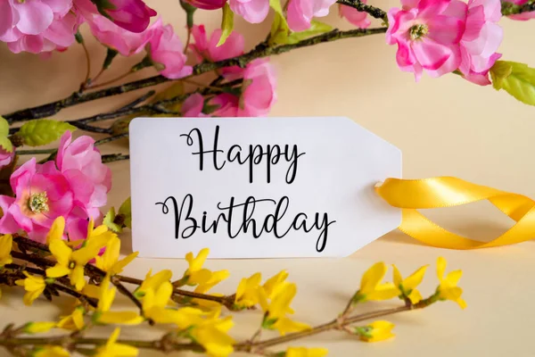 Spring Flower Arrangement With White Label With English Text Happy Birthday. Colorful Flower Branch Decoration With Yellow And Purple Blossoms.