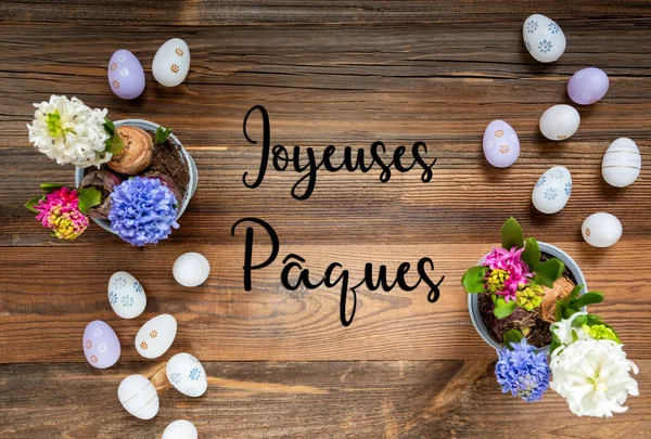 复活节平铺法文本Joyeuses Paques意为复活节快乐 有复活节彩蛋装饰和装饰品的花朵 具有木制 古色古香背景的百合花排列 — 图库照片