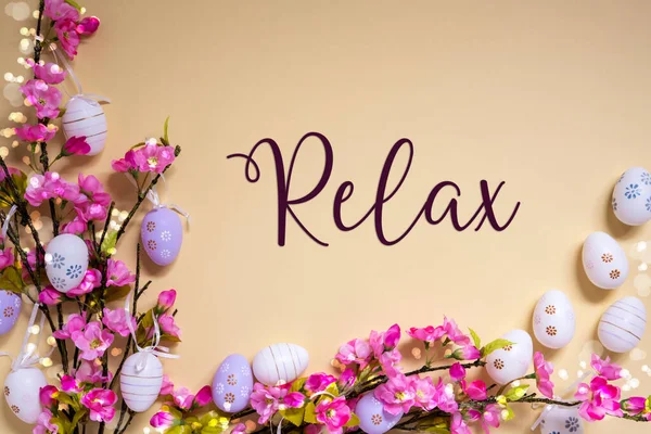 English Text Relax On Beige Background. Pink And Purple, Shiny And Bright Spring Flower Arrangement With Easter Egg Decoration.