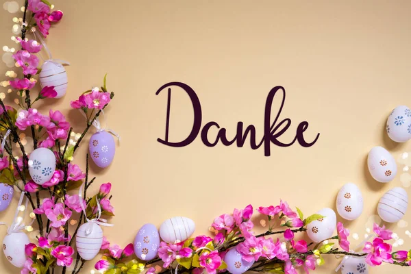 ドイツ語のテキストダンクはベージュの背景に感謝を意味します イースターエッグデコレーションでピンクとパープル 光沢と明るい春の花のアレンジメント — ストック写真