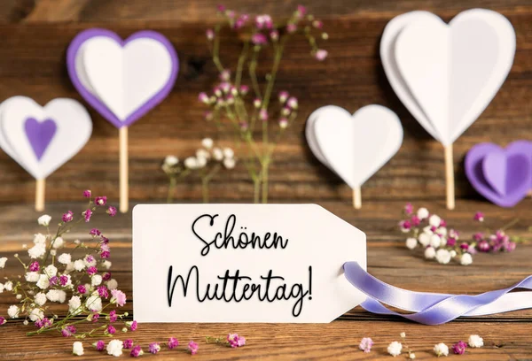 带有德语文字的标签Schoener Muttertag意味着快乐母亲日 紫丁香装饰与春花布置 具有木制背景的心脏符号 — 图库照片