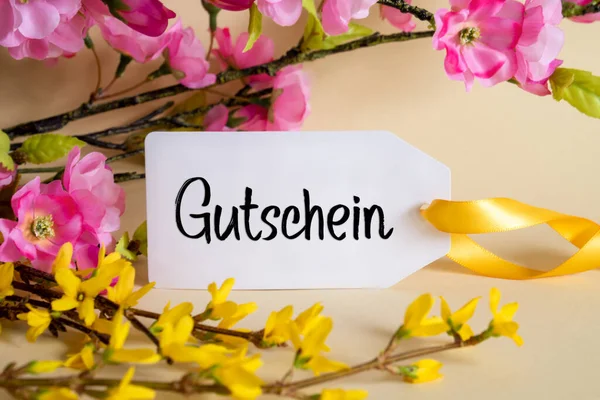 春のフラワーアレンジメントドイツ語のテキストとホワイトラベルGutscheinはバウチャーを意味します 黄色と紫の花とカラフルな花の枝の装飾 — ストック写真