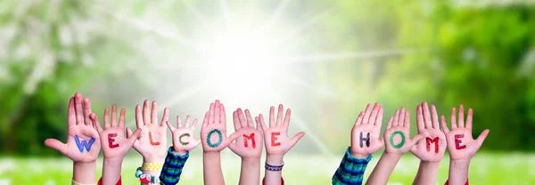 孩子们手握多彩的英语单词欢迎回家 阳光碧绿的草场作为背景 — 图库照片