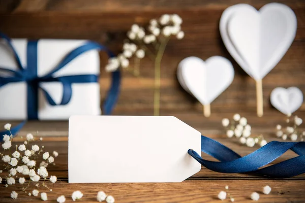 無料テキスト用のコピースペース付きのラベル 青い弓 ハートと花のプレゼントのような白い祭りの装飾 ヴィンテージ木製の背景 — ストック写真