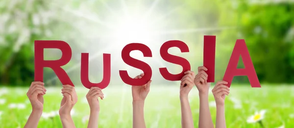 人或人的手建设英语单词俄罗斯 阳光碧绿的草场作为背景 — 图库照片